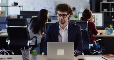 Ofis çalışanları arka plan üzerinde başkaları ile büyük modern ofis alanı içinde belgili tanımlık laptop üzerinde gözlük yakışıklı adam. İçinde