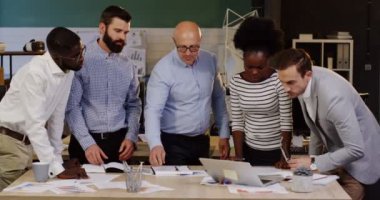 Çok etnik çalışan kendi patron hakkında yeni strateji proje belgeleri, grafikleri, grafik ile masa etrafında duran ve mali ile danışmanlık grubu üzerinde raporlar. İçinde