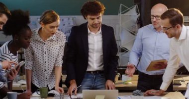 Genç office ortak çalışanlar veriler hakkında konuşmak ve yeni bir proje patronlarıyla tartışırken karışık ırklar. Masanın bir dizüstü bilgisayar ve belgeler. Güzel ofis içinde