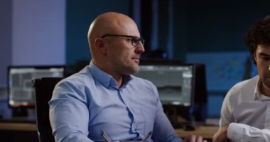 Çekici erkek masa etrafında oturmuş ve neşeyle işlerini rahat ofiste patron ile akşam geç tartışıyor. Kapalı