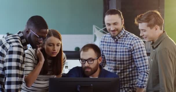 Joven equipo multiétnico de trabajadores hablando y creando un plan de negocios para un proyecto de puesta en marcha en la computadora. Equipo de oficina trabajando en la cómoda sala de oficina . — Vídeo de stock