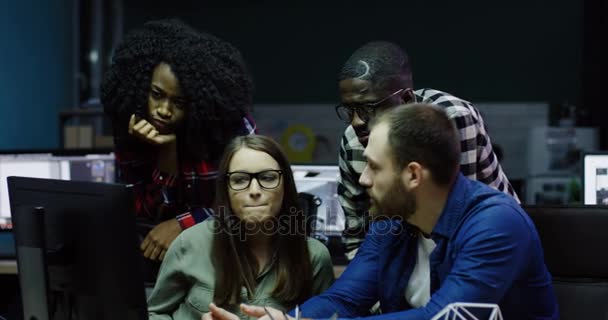 Több-etnikumú csapat fiatal munkatársak beszélünk és létrehozása a projekt üzleti tervet a számítógépen késő esténként. Hivatal csapat a férfiak és nők a kényelmes office szobában. — Stock videók