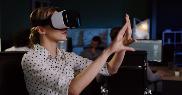 Jeune jolie femme ayant un casque VR à son lieu de travail dans la nuit. Employé de bureau en lunettes VR. Dans le grand espace de bureau — Video