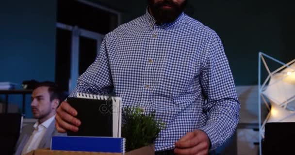Primer plano de un hombre guapo con barba empacando sus cosas dentro de la caja en la oficina a altas horas de la noche y marchándose porque perdió su trabajo. De interior — Vídeo de stock