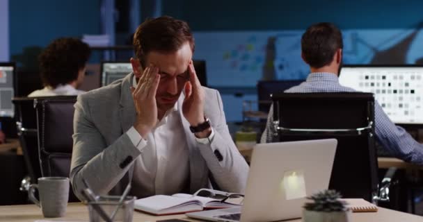 Hombre de negocios cansado trabajando hasta tarde en la computadora en la oficina y tratando de descansar. En interiores — Vídeos de Stock