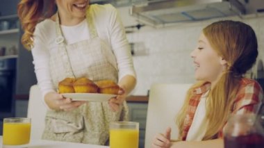İyi görünümlü anne kızıyla birlikte kek için plaka ve thay her iki kokulu onlara masada mutfakta geliyor önlük. İçinde