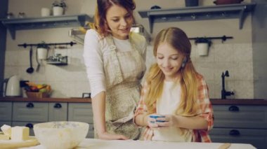 Çekici anne daugh boyu kek hazırlama ve formlarda koyarak sarışın kızı izliyor. Anne onları fırına kek formlarla zannetme. Kapalı
