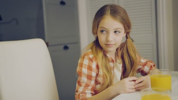 Primer plano de la madre poniendo un plato de magdalenas en la mesa delante de su hija y la chica bonita abrazándola por eso. Un retrato. De interior — Vídeos de Stock