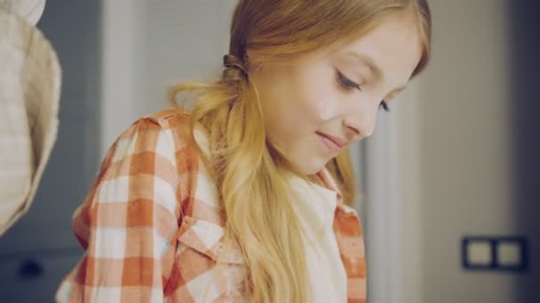 Primer plano de la linda chica rubia haciendo formas con un daugh y sonriendo junto a su madre en la cocina. Un retrato. Adentro. — Vídeo de stock