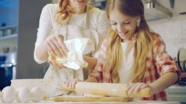 Anne ve kızı bir daugh kurabiyeler için yapma. Bir un bir kızı o akşam mutfak masasında yoğurma sırasında dökülen anne. Portre vurdu. İçinde