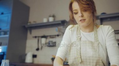 Bir daugh rahat modern mutfakta bir cam kasede yoğurma genç beyaz kadının kapatın. Portre vurdu. Kapalı