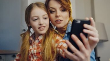 Güzel kızı ve anne birbirine yakın oturan ve evde odada siyah smartphone selfies yapma kapatın. Kapalı. Portre