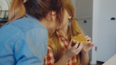 Anne ve kızı mutfak masasında fıstık ezmesi ile ekmek yeme bir kız iken burun sürtme kapatın. portre vurdu. Kapalı