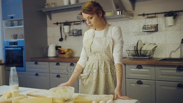 Retrato da jovem mulher encantadora no avental e com farinha no rosto fazendo uma filha e sorrindo para a câmera na cozinha. Interior — Vídeo de Stock