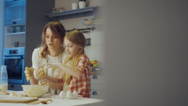 Счастливые мать и дочь месить до Daugh для кексов или печенье вместе в вечернее время в современной красивой кухне. В помещении — стоковое видео