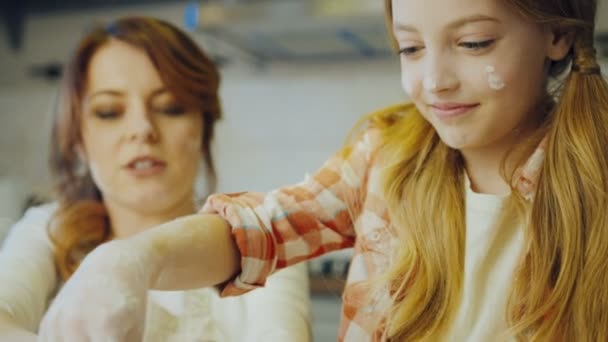 Gros plan de la jolie fille ayant ici les mains avec une farine parce qu'elle pétrit une bosse et que sa mère rit. Prise de vue portrait. À l'intérieur — Video