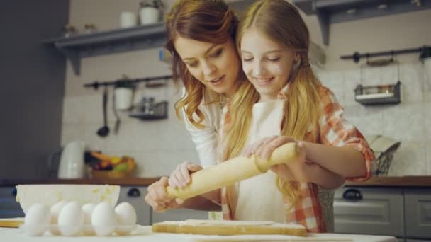 Retrato de la madre enseñando a su hija a hacer un daugh en la mesa de la cocina moderna. De interior — Vídeo de stock