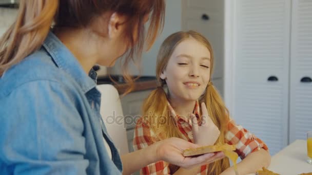 La giovane madre stende il burro di arachidi sul pane e lo dà alla sua graziosa figlia da mangiare nella cucina moderna. Chiudete. Interni — Video Stock