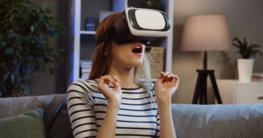 Genç sarışın kadının bir Vr kulaklık sahip ve akşamları evde kanepede korkunç jest yapma Vr bardaklarda kapatın. Portre. Kapalı