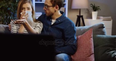 Onun sarışın sakinleştirmeye çalışan yakışıklı genç adam portre çekim güzel karısı çünkü o bir drama film izledikten sonra peçeteye ağlıyor. Evde akşamları. İçinde