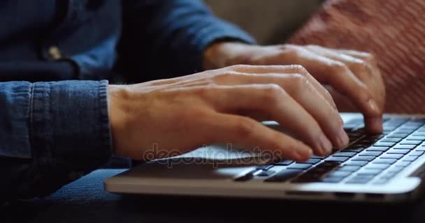 Sluit uit de Kaukasische mans handen in jeans mouwen taping op de laptop computertoetsenbord op mans knieën. Indoor — Stockvideo