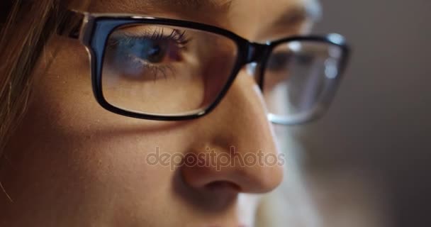 De cerca desde el lado de la caucásica hermosa cara de mujer en gafas mientras trabaja en el ordenador. Un retrato. De interior — Vídeo de stock