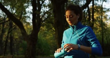 Sunset bulvarında parkta koşu sonra termos çekici sportif kadın içme suyu. Açık havada