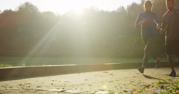 Zeitlupe eines sportlichen Paares, das seinen Lauf im Park beendet. das Sonnenlicht am frühen Herbstmorgen. Müde, aber glücklich. im Freien. — Stockvideo