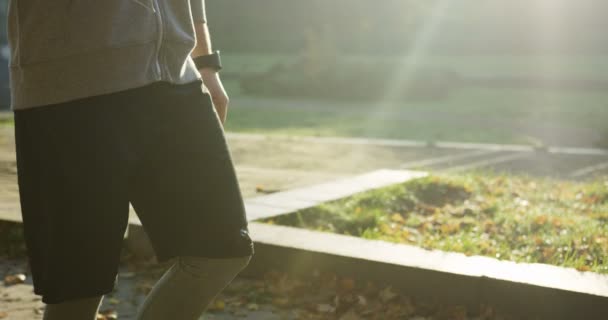 Slow motion av attraktiv man jogger promenader i parken och tejpning på telefonen i morgon solljus. Utomhus. Kameran går upp — Stockvideo