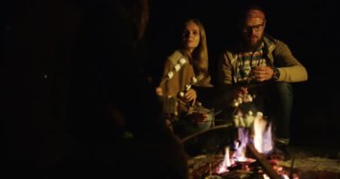 Grup hipsters arkadaşıyla, şarkı, gitar çalmak, marshmellows şenlik üzerinde pişirme ve onları gece zamanında yemek. Dışarıda