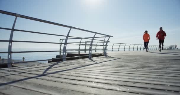 Young couple running on the pier near sea. Beautiful sunny day. Outside. Shot from below — Stock Video