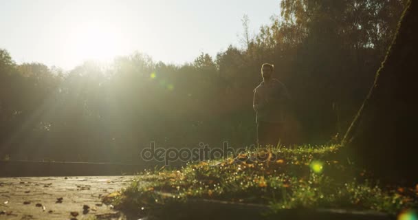 Silhouette da jogger maschile che corre e si avvicina alla telecamera al mattino al parco. Il tempo soleggiato. All'aperto. Dal basso — Video Stock