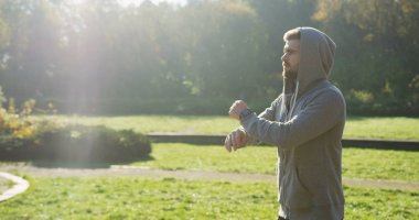 Bir başlıklı sakallı yeşil parkta egzersiz çekici genç adam. Güneşli sabah. Açık