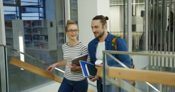 Молода пара кавказьких студентів ходити вгору по сходах і радісно говорили в бібліотеці сучасних приємно. Всередині — стокове відео