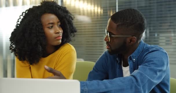 Primer plano de los trabajadores de oficina jóvenes afroamericanos discutiendo su nuevo proyecto en el escritorio con la computadora. Un retrato. Adentro. — Vídeos de Stock