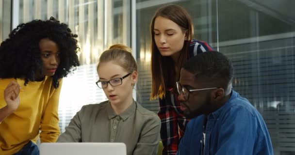 Группа молодых смешанных рас студентов мужского и женского пола обсуждают свой учебный проект за компьютером в красивой комнате. Портрет. В помещении — стоковое видео