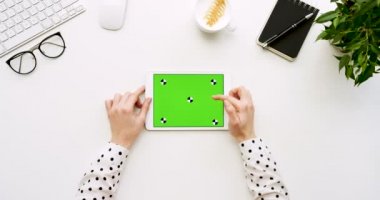 Üstten Görünüm beyaz Ofis Masası ve yeşil ekran ve eller üzerinde kayıt olan beyaz tablet bilgisayar. Yatay. Yanında başı işleri. Chroma anahtar. Hareket izleme