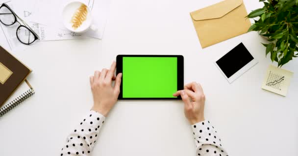 Vista superior en el escritorio de la oficina blanca y tableta negra con pantalla verde y manos femeninas pegadas en ella. Horizontal. Cosas de oficina al lado. Clave de croma . — Vídeos de Stock