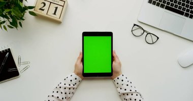 Üstten Görünüm Ofis Masası ve yeşil ekran ve eller üzerinde kayıt olan siyah tablet bilgisayar. Dikey. Yanında başı işleri. Chroma anahtar.