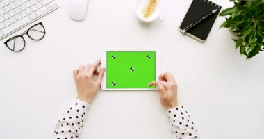 Üstten Görünüm beyaz Ofis Masası ve yeşil ekran ve eller üzerinde kayıt olan beyaz tablet bilgisayar. Yatay. Yanında başı işleri. Chroma anahtar. Hareket izleme