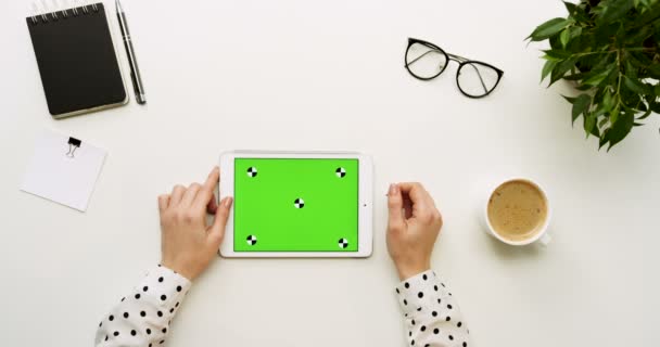 사무실 책상 및 녹색 스크린 및 여성의 손에 그것에 찍고 흰색 태블릿 컴퓨터에서 최고 볼 수 있습니다. 수평. 오피스 물건 고 옆에 커피입니다. 크로마 키입니다. 모션 추적 — 비디오