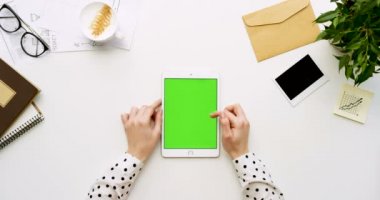 Üstten Görünüm beyaz Ofis Masası ve yeşil ekran ve eller üzerinde kayıt olan beyaz tablet bilgisayar. Dikey. Yanında başı işleri. Chroma anahtar.