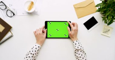 Üstten Görünüm beyaz Ofis Masası ve yeşil ekran ve eller üzerinde kayıt olan siyah tablet bilgisayar. Yatay. Yanında başı işleri. Chroma anahtar. Hareket izleme