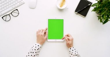 Üstten Görünüm beyaz Ofis Masası ve yeşil ekran ve eller üzerinde kayıt olan beyaz tablet bilgisayar. Dikey. Yanında başı işleri. Chroma anahtar.