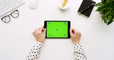 Üstten Görünüm beyaz Ofis Masası ve yeşil ekran ve eller üzerinde kayıt olan siyah tablet bilgisayar. Yatay. Yanında başı işleri. Chroma anahtar. Hareket izleme