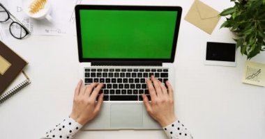 Üstten Görünüm ofis masaları olan dizüstü bilgisayar ile yeşil ekran ve üzerinde taping eller üzerinde. Yanında başı işleri. Chroma anahtar.