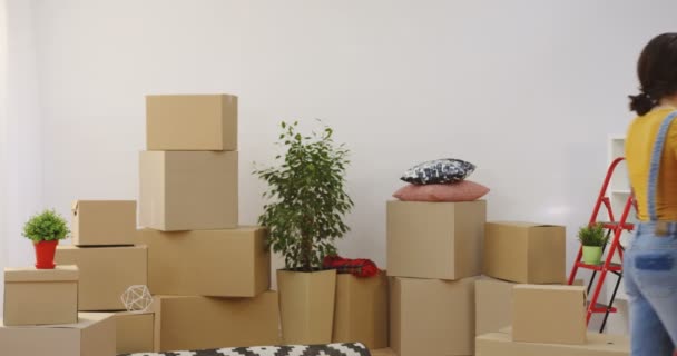 Молодые кавказские мужчина и женщина, переезжая домой вещи и коробки около гостиной, переезжая вместе. В помещении — стоковое видео