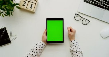 Üstten Görünüm Ofis Masası ve yeşil ekran ve eller üzerinde kayıt olan siyah tablet bilgisayar. Dikey. Yanında başı işleri. Chroma anahtar.