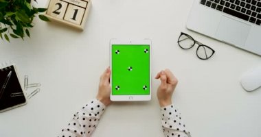 Üstten Görünüm Ofis Masası ve yeşil ekran ve eller üzerinde kayıt olan beyaz tablet bilgisayar. Dikey. Yanında başı işleri. Chroma anahtar. Hareket izleme