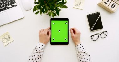 Üstten Görünüm Ofis Masası ve yeşil ekran ve eller üzerinde kayıt olan siyah tablet bilgisayar. Dikey. Yanında başı işleri. Chroma anahtar. Hareket izleme